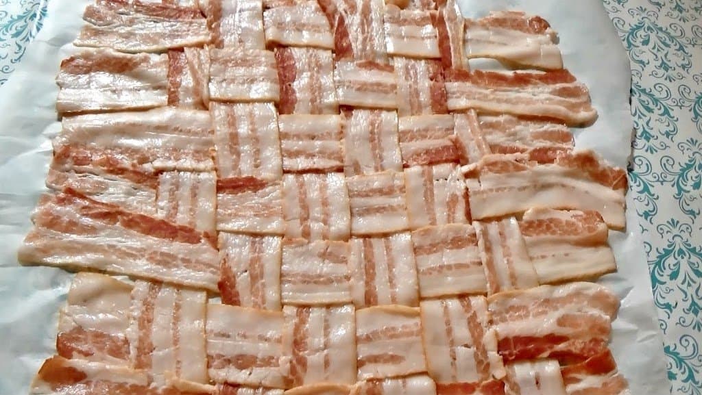 Bacon weave for stuffed pork loin laying on a piece of parchment paper.
