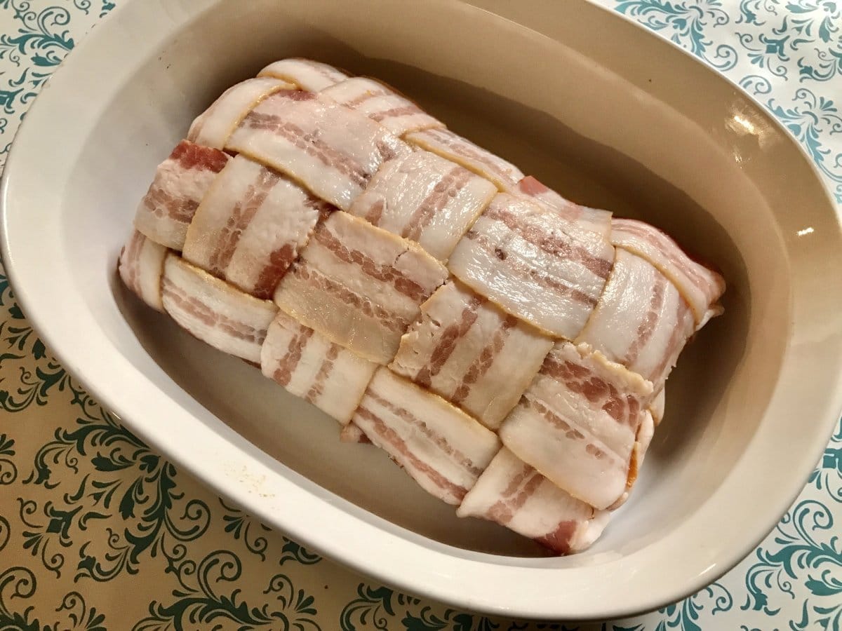 Grilled Pork Loin Wrapped in Bacon in a white cooking dish.